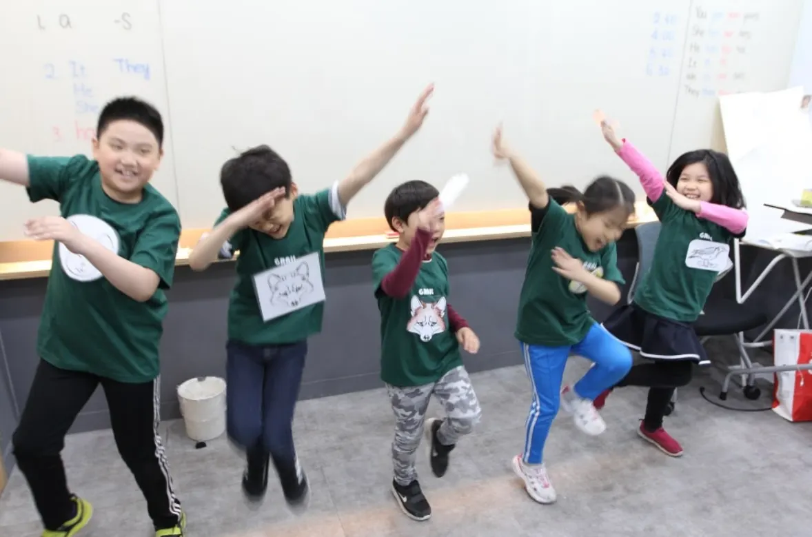 Students in GRAIL T-shirts jumping and posing in front of a whiteboard of pronouns