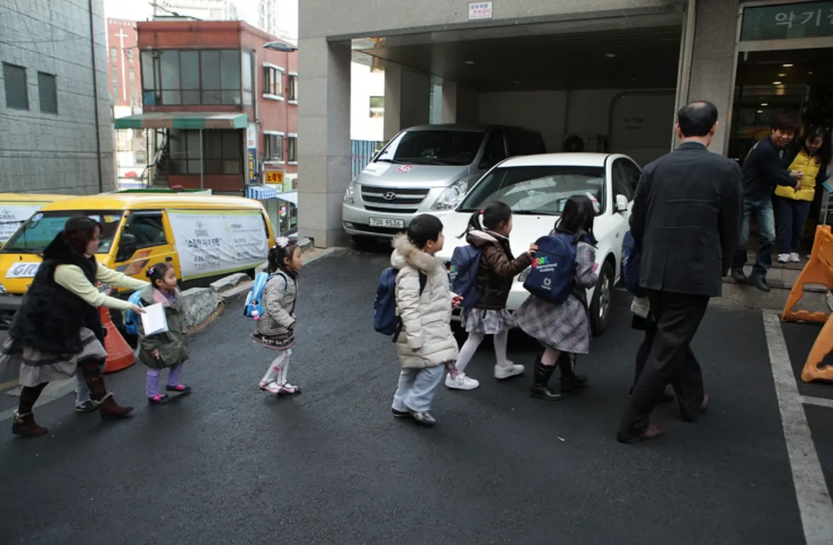 Children walking in a line from the shuttle to the academy