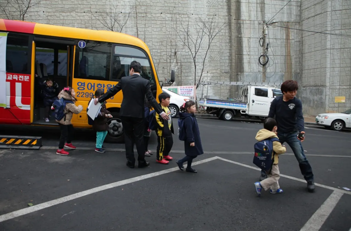 Children boarding GRAIL shuttle bus No. 1 with a teacher