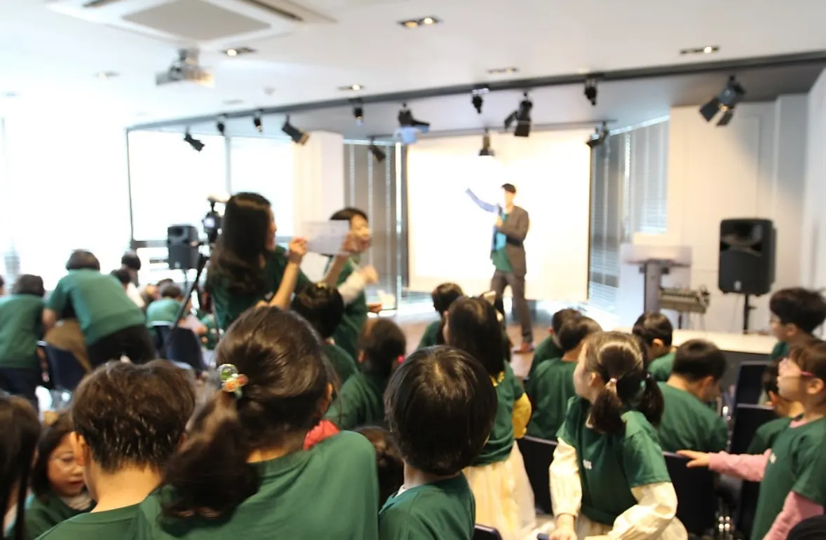 Students in green GRAIL T-shirts watching a presentation in the event hall