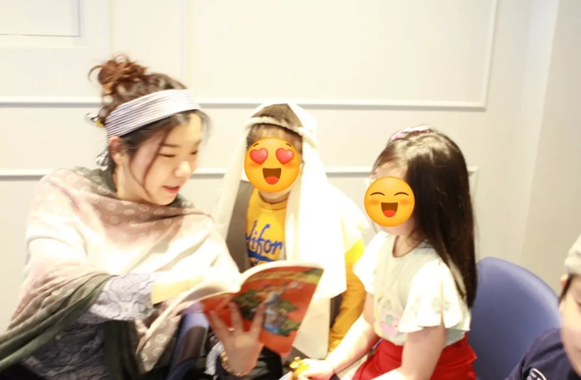 A teacher in costume reading a storybook to two children