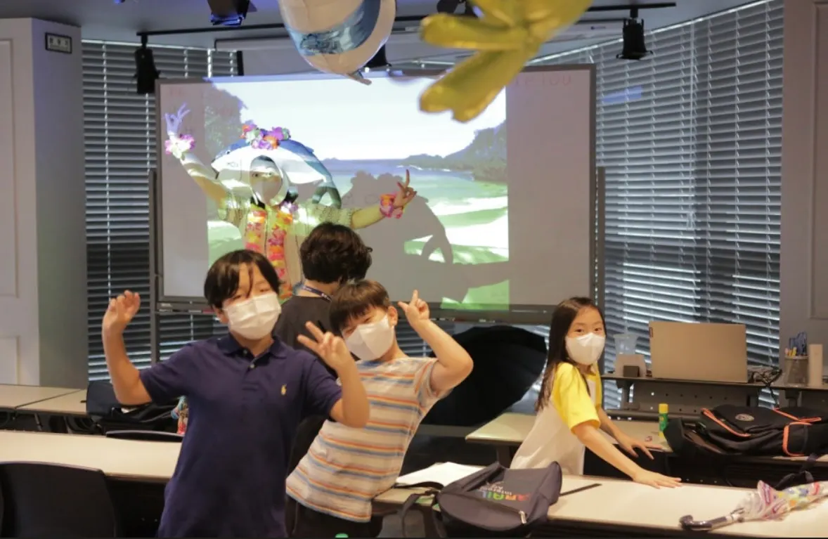 Students posing in front of a tropical island projection during a themed class